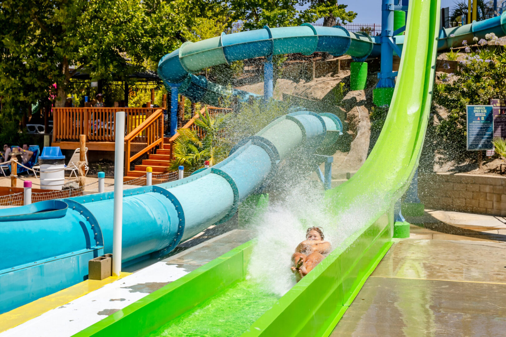 Person splashing down a green waterslide