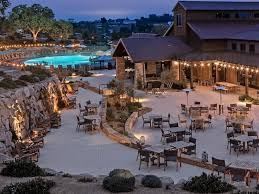 Outdoor dining area near a pool at dusk with warm lighting.