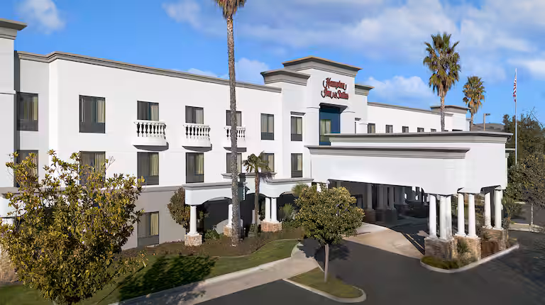 Exterior view of a Hampton Inn hotel building under a blue sky.