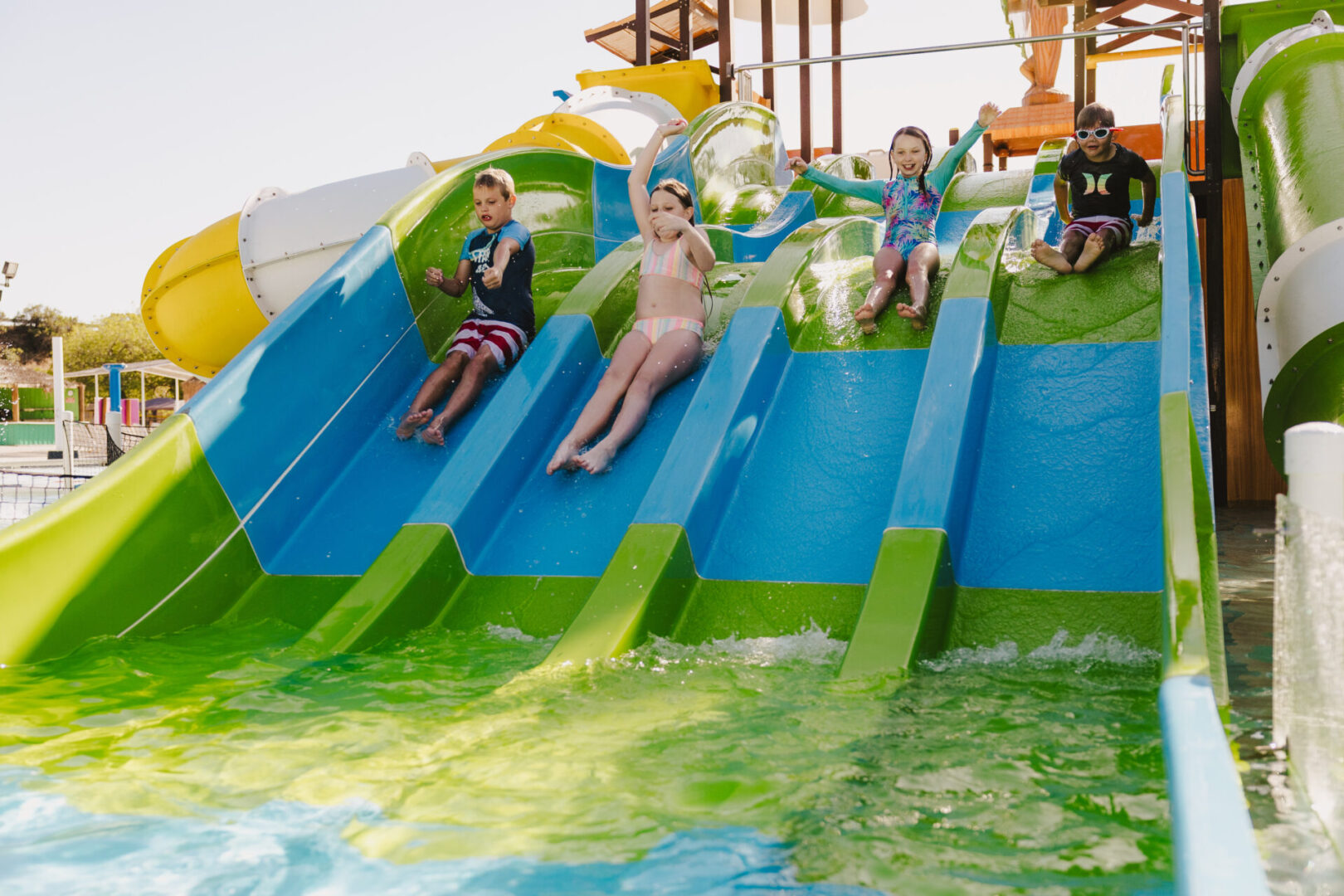 Children sliding down a water slide into a pool.