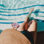 Person relaxing by pool with drink.
